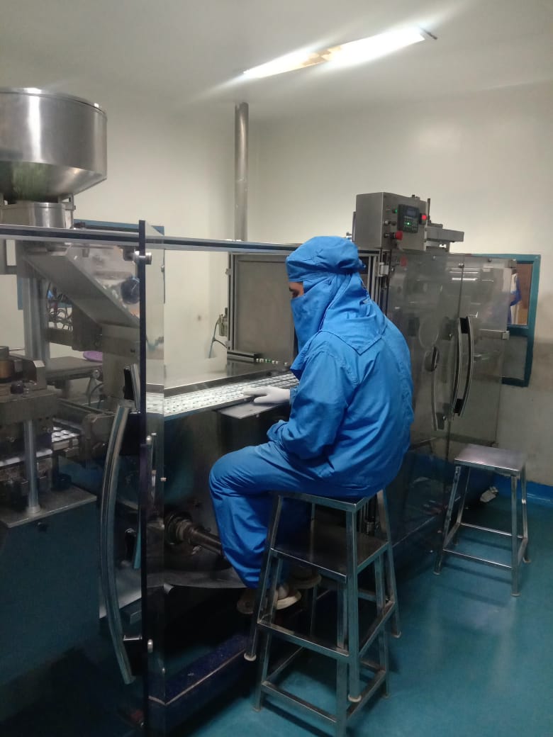 Operator in cleanroom suit at tablet machine